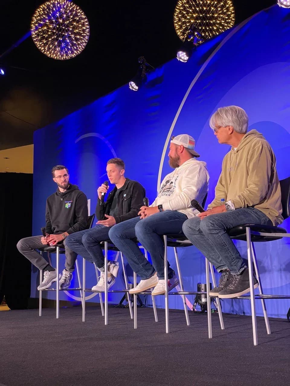 Four speakers seated on stage during a panel discussion.